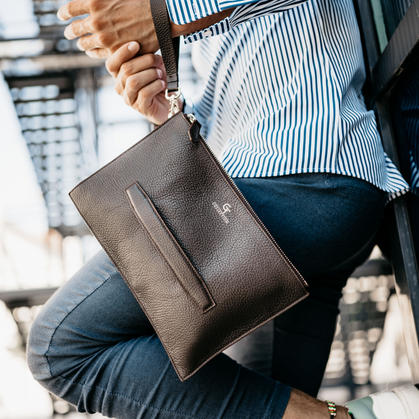 Brown leather wrist hand bag with gold zipper, front strap pocket and metal ring