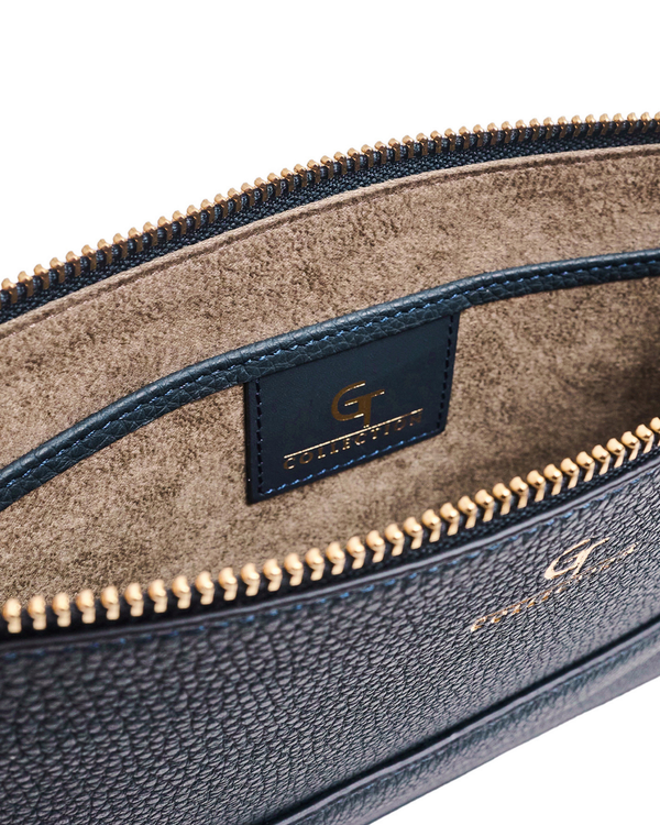 Blue leather pouch interior view with tan lining, logo patch, gold-tone zipper edge.