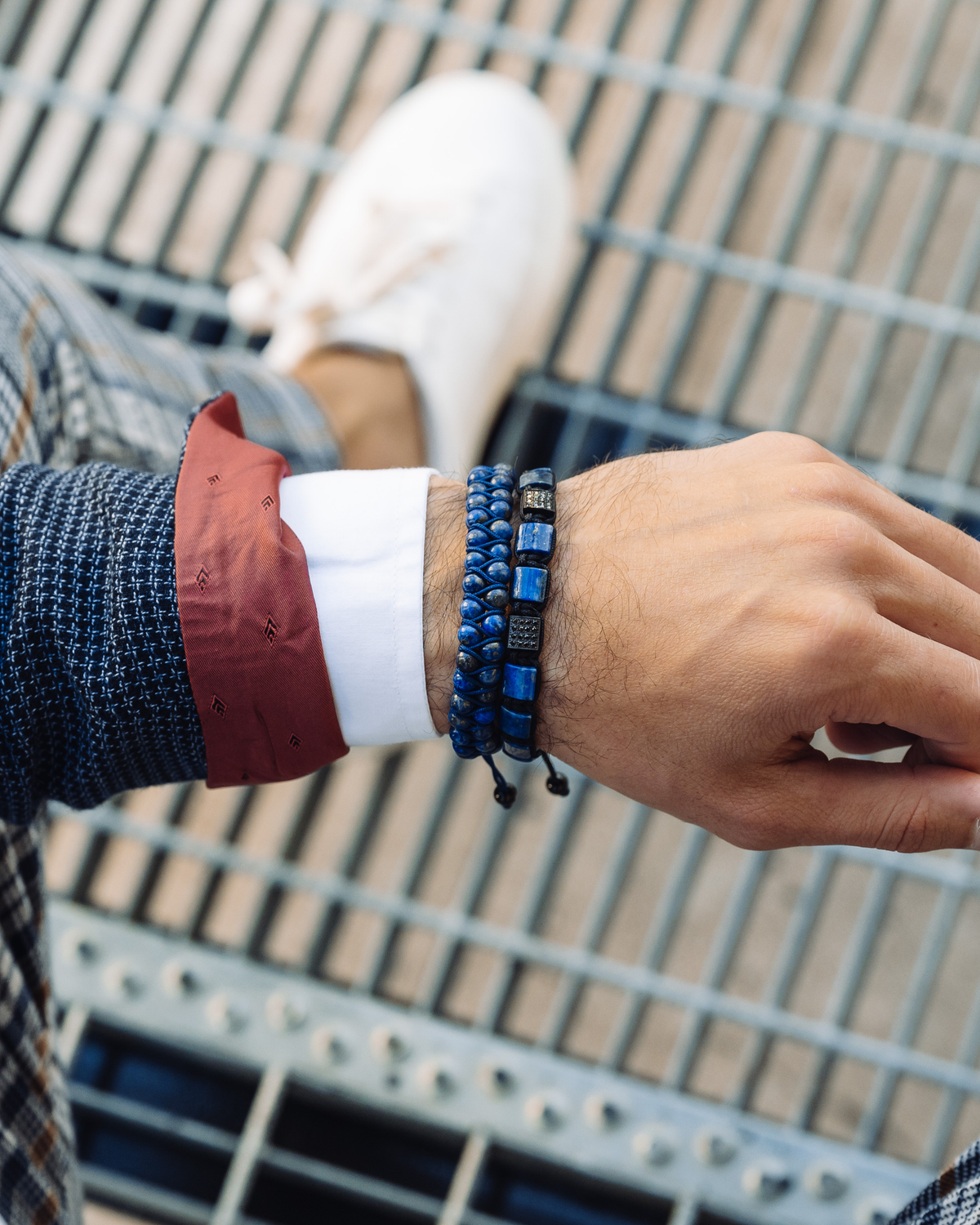 Blue beaded double-row bracelet on wrist with rectangular black logo clasp
