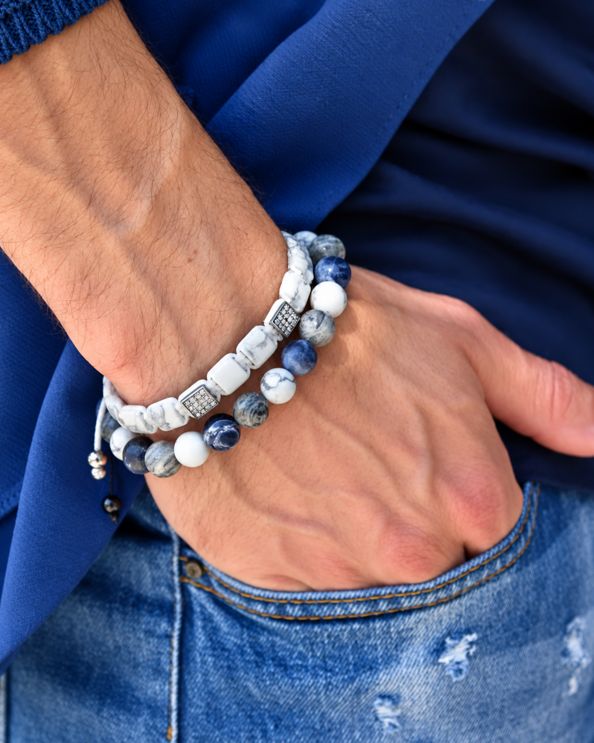 Stacked bracelets on wrist featuring blue and white stones with black cord detail