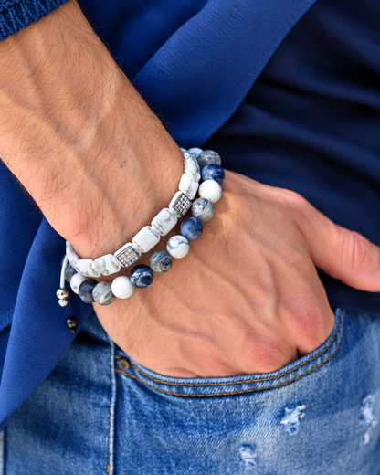 Stacked bracelets on wrist featuring blue and white stones with black cord detail
