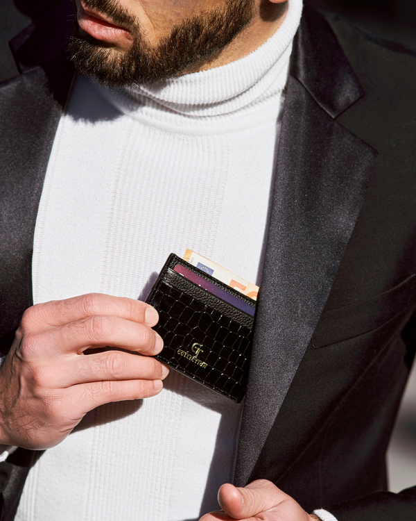 Black croc-embossed leather card holder with cards visible, gold logo on front