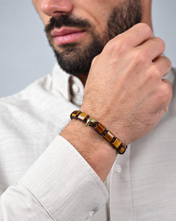Tiger eye beaded bracelet on wrist with gold eagle charm and brown cord
