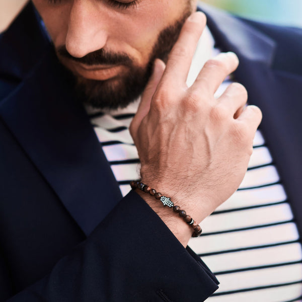 Tiger-eye bead bracelet on man's wrist, black cord and Hamsa hand charm