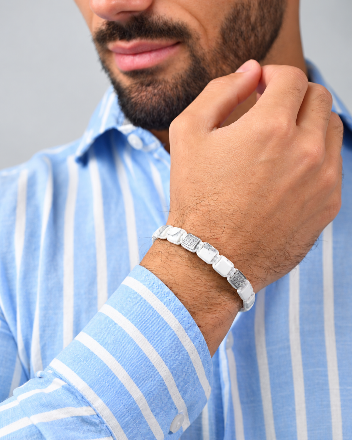 White marble-effect bead bracelet worn on wrist with black logo centerpiece