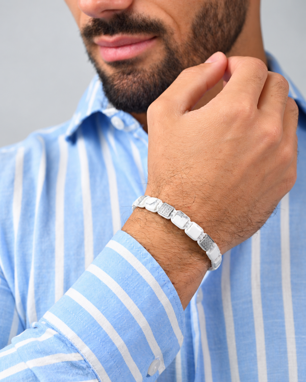 White marble-effect bead bracelet worn on wrist with black logo centerpiece