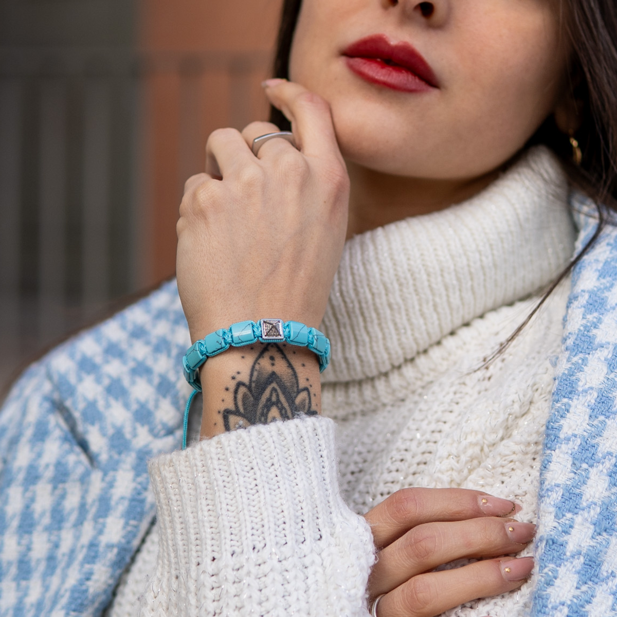 Turquoise flat bead bracelet on wrist with silver-tone clasp and geometric center plate