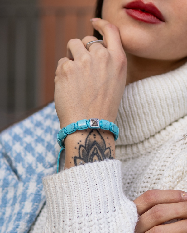 Turquoise flat bead bracelet on wrist with square center charm