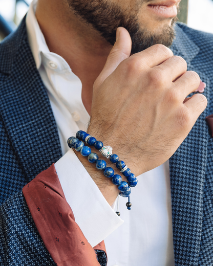 Blue beaded bracelets with charm on wrist, two-piece stack with cord and metal accents