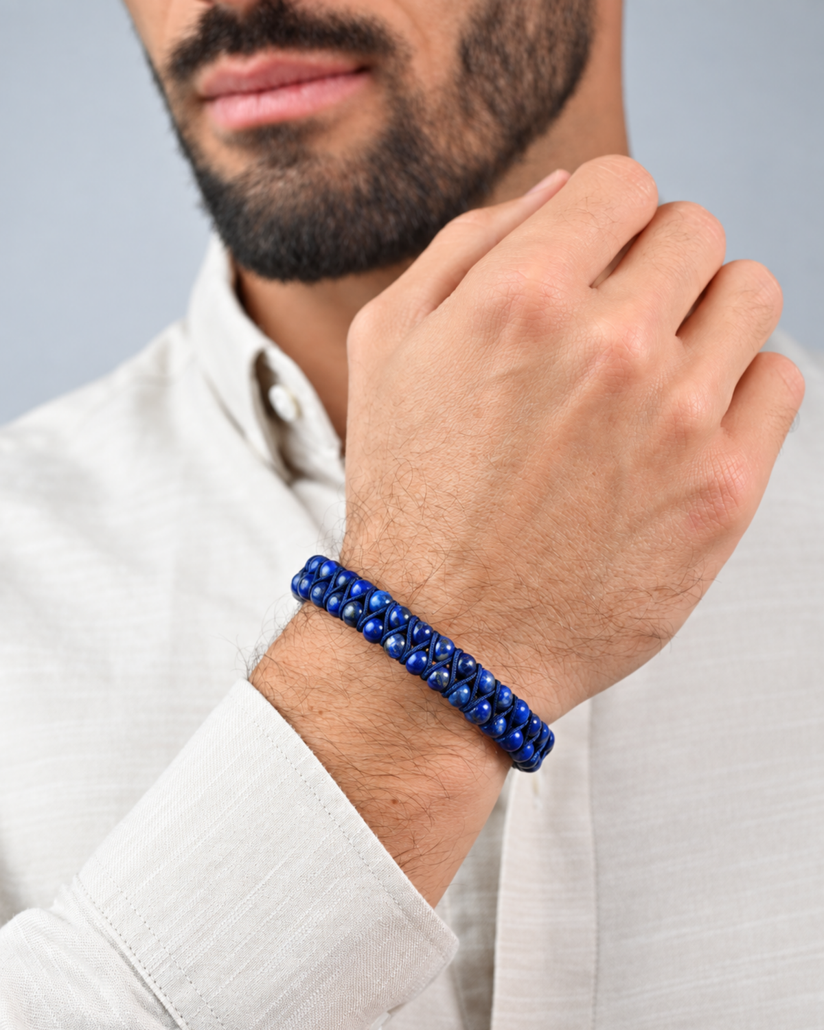 Blue beaded double-row bracelet on wrist with black clasp and braided cord
