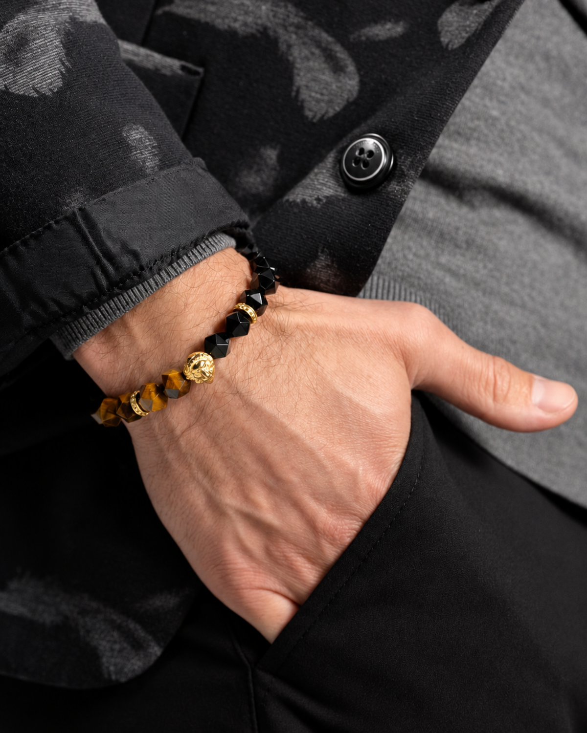 Lion charm beaded bracelet on wrist featuring black faceted stones and tiger-eye beads