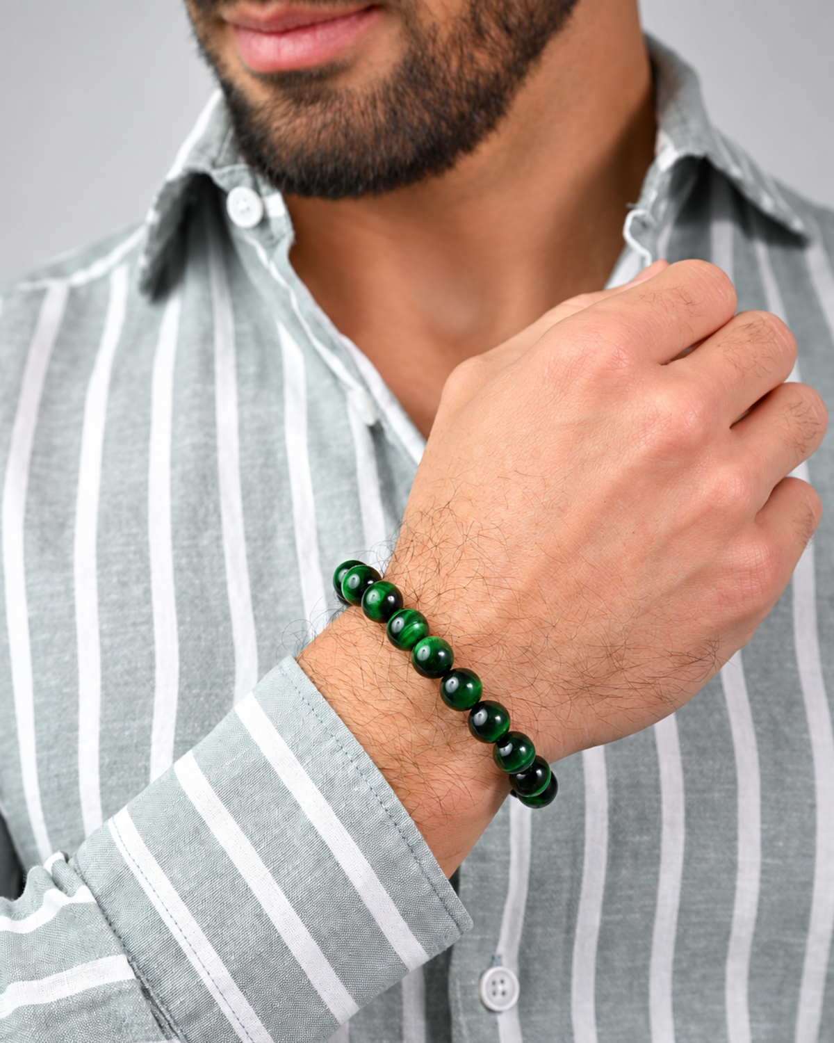 Green bead bracelet worn on wrist with black cord and center bar