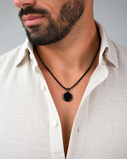 Black octagonal pendant necklace worn at chest with white shirt