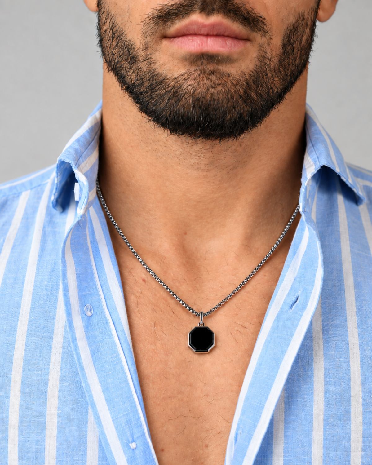 Men's silver-tone pendant necklace with centered black octagonal pendant at chest