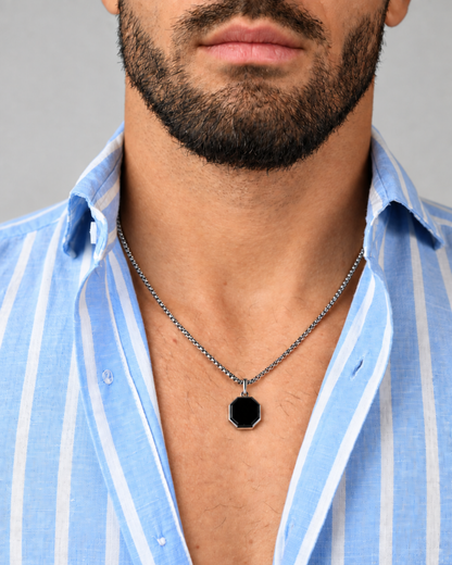 Men's silver-tone pendant necklace with centered black octagonal pendant at chest