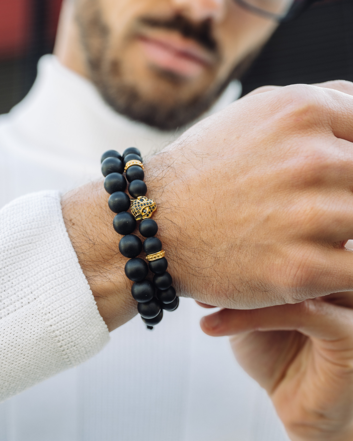 Black beaded bracelet stack on wrist with gold-toned charm
