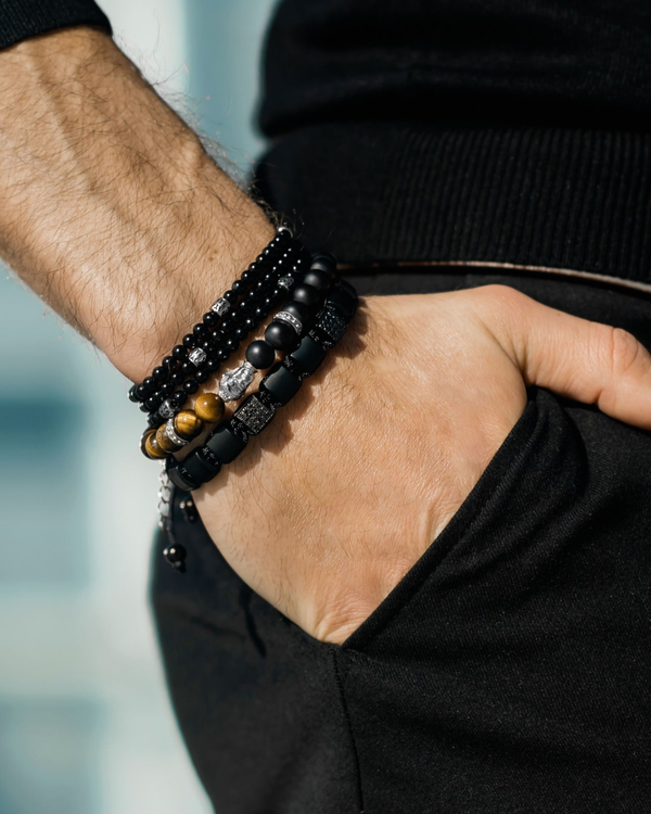 Wrist bracelet with matte black beads and tiger-eye accents, silver Buddha charm, braided band