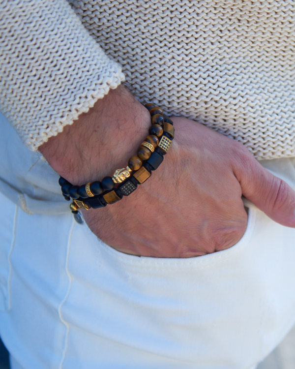 Bracelet on wrist: matte black onyx and gold-tone bead stack with tiger eye highlights