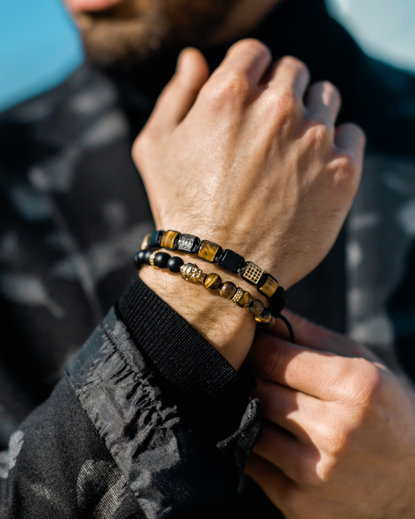 Bracelet on wrist: tiger eye and black onyx beads with gold-tone accents and charm