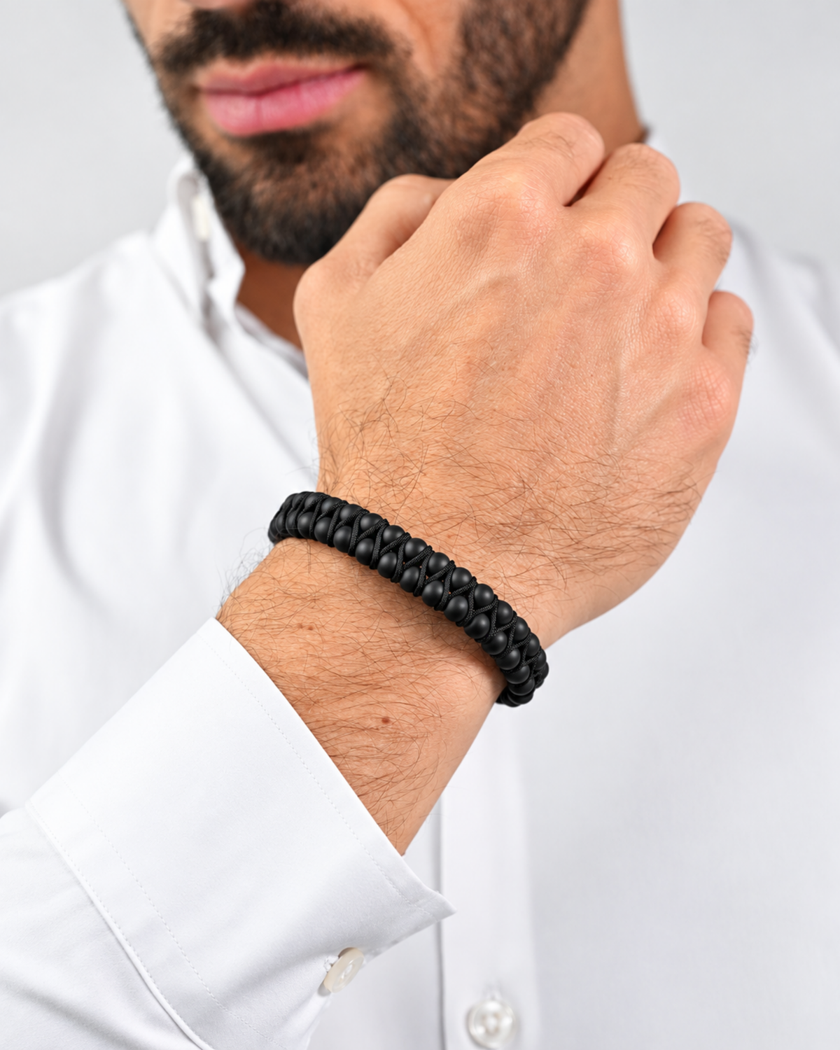 Black double-row bead bracelet on wrist with braided cord and metal clasp