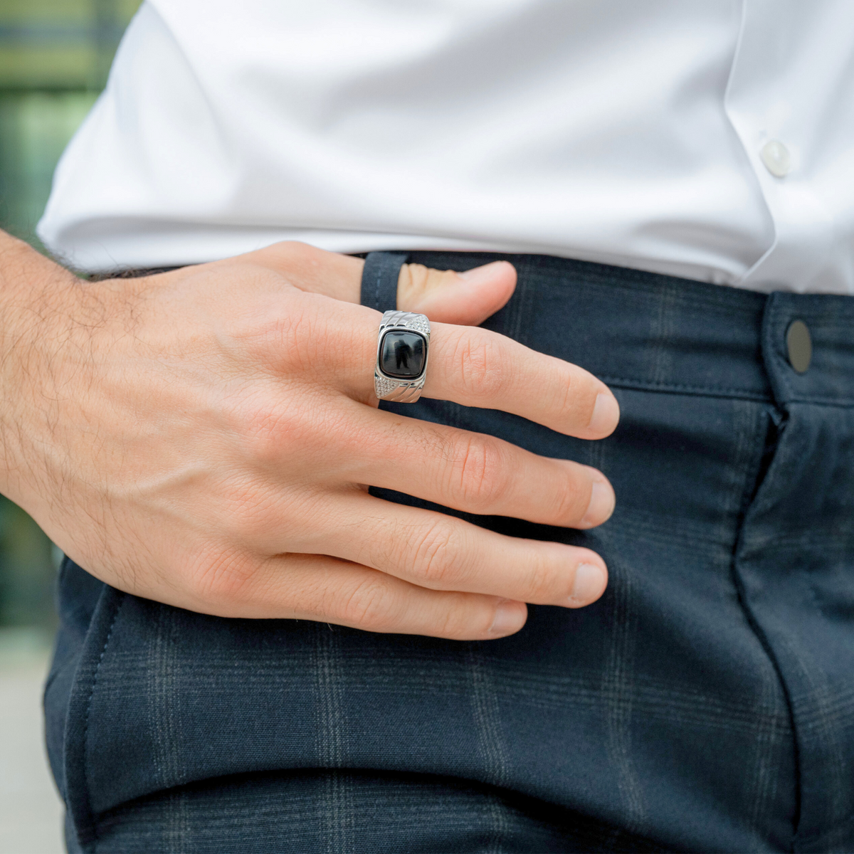 Silver onyx-stone ring on hand resting near denim