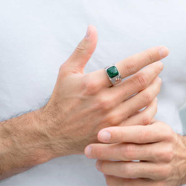 Man's hand wearing a sterling silver ring with green malachite oval cabochon