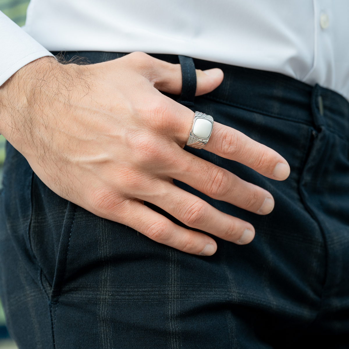 Sterling silver ring with white Howlite on man's hand over dark jeans