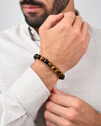 Tiger eye bead bracelet on a man’s wrist with black end beads and braided cord