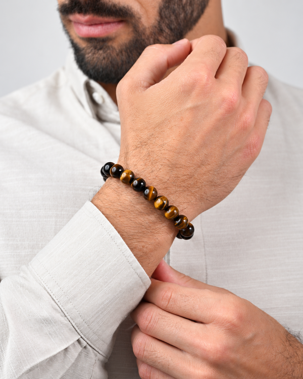 Tiger eye bead bracelet on a man’s wrist with black end beads and braided cord