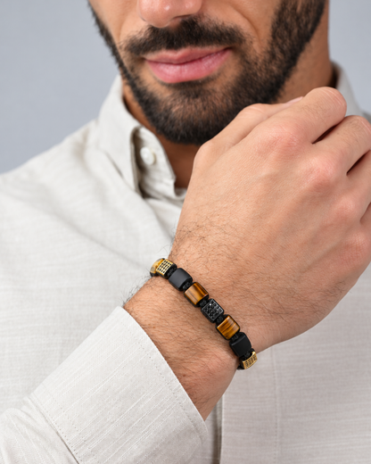 Bracelet on forearm: black cord with tiger eye and onyx beads, gold accent spacers
