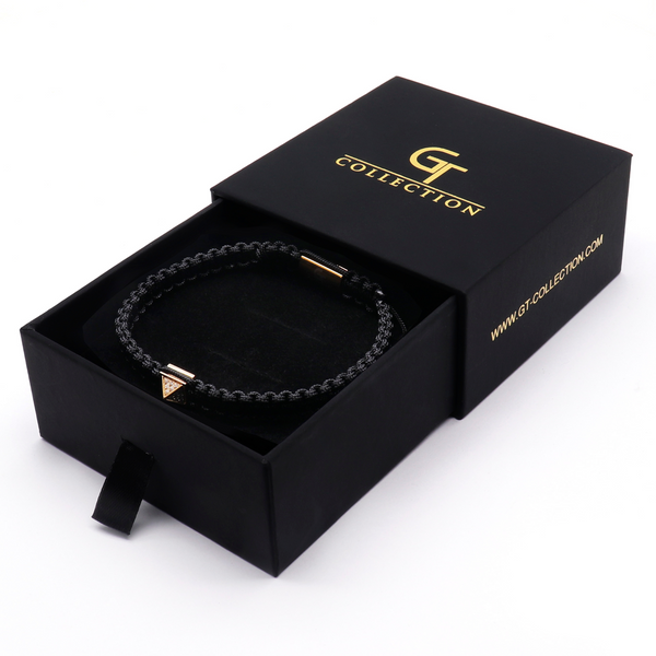 Black cord pyramid bracelet in open box with gold clasp detail