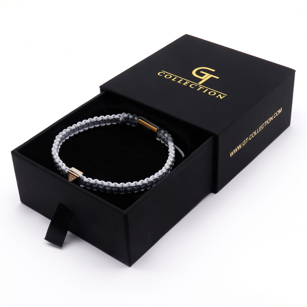Men's pyramid bracelet shown in black gift box with light gray cord and gold pyramid clasp