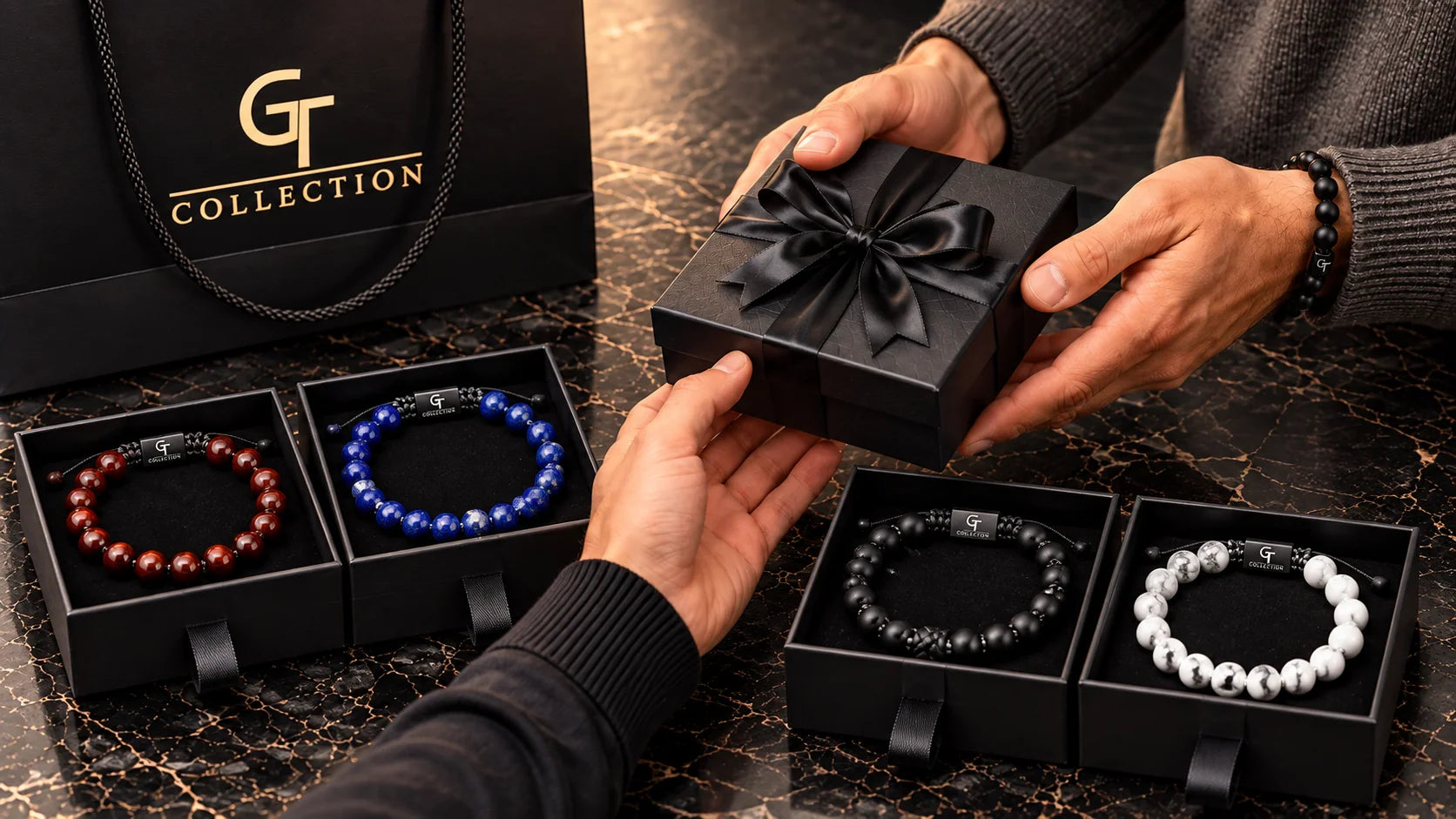Man giving a GT Collection black gift box, with red, Lapis Lazuli and Black Onyx bead bracelets in gift boxes